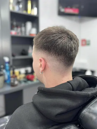 Low fade la ceafă și păr scurt texturat, fotografiat din spate în salon